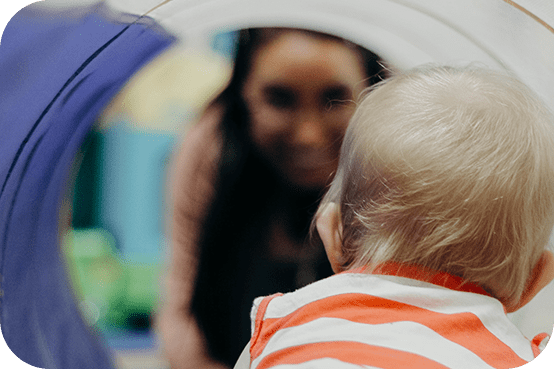 A baby looking at its reflection in the mirror