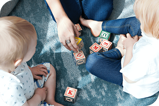 A group of people sitting on the ground playing with blocks.