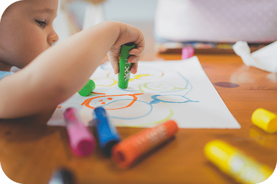 A child is playing with markers on paper.