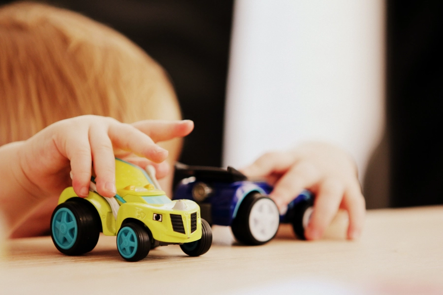 A child playing with toy cars on the table.