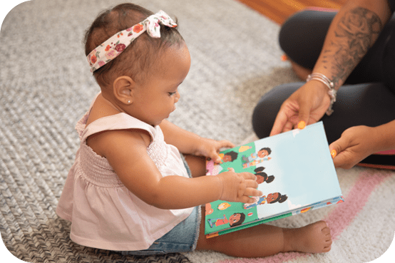 A baby is sitting on the floor reading a book.
