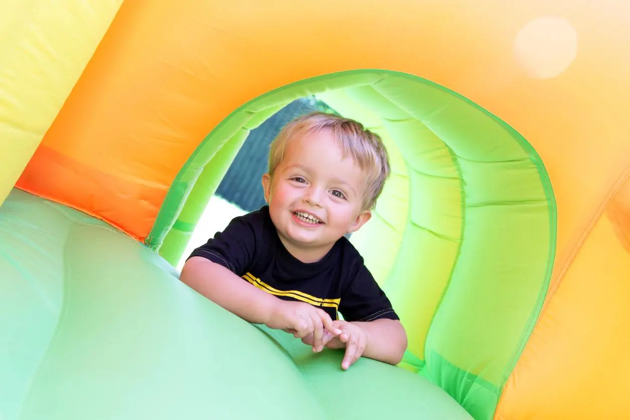 A little boy is smiling in an inflatable play area.